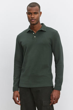 A man wearing a Velvet by Graham & Spencer MIKE POLO, a forest green long-sleeve shirt made of piqué cotton, stands against a plain white background.