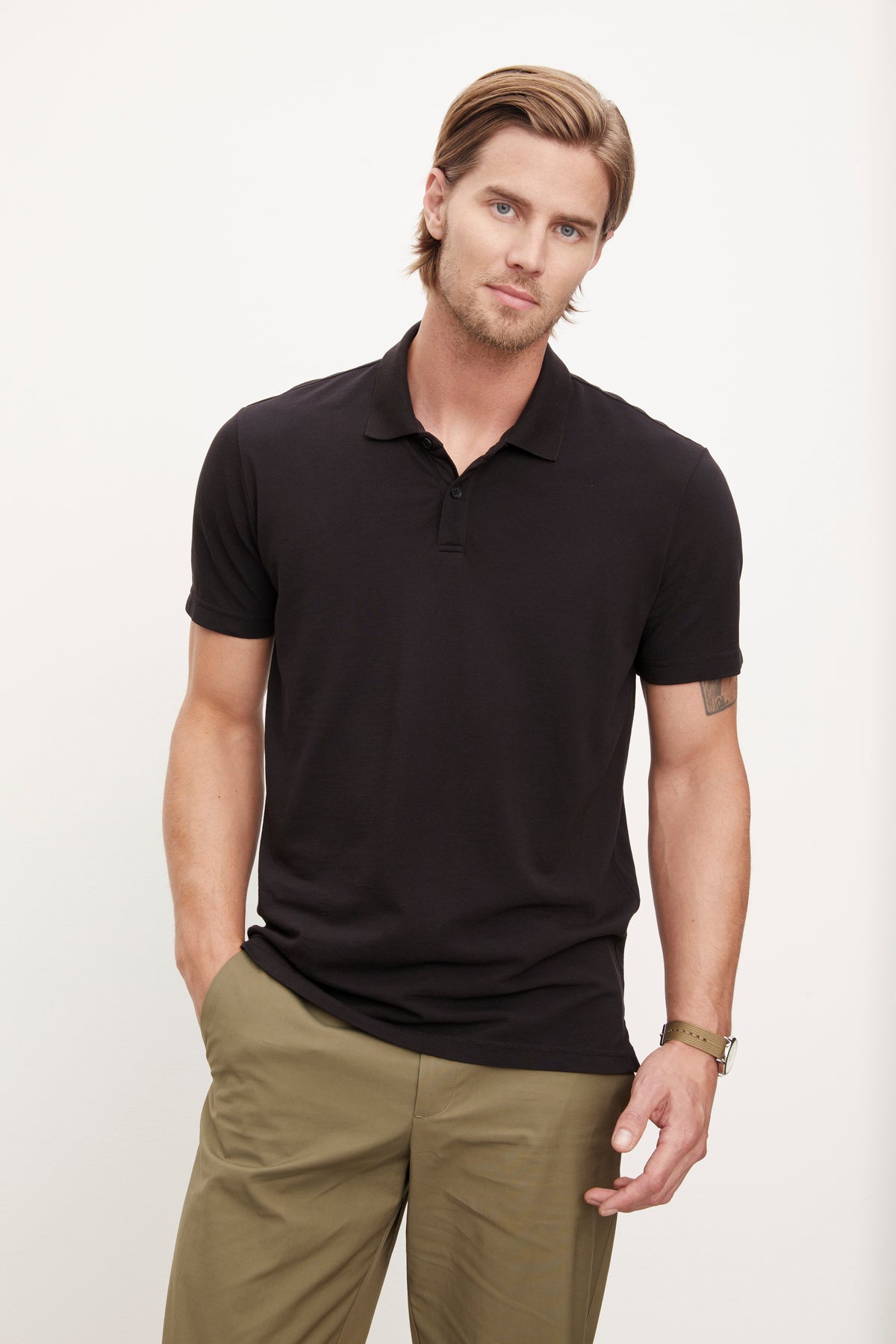   A man wearing a black Velvet by Graham & Spencer Willis Pique Polo shirt and khaki pants. 