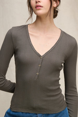 A woman models the WINONA POINTELLE HENLEY by Velvet by Graham & Spencer with blue jeans against a neutral background, highlighting this feminine everyday layer.
