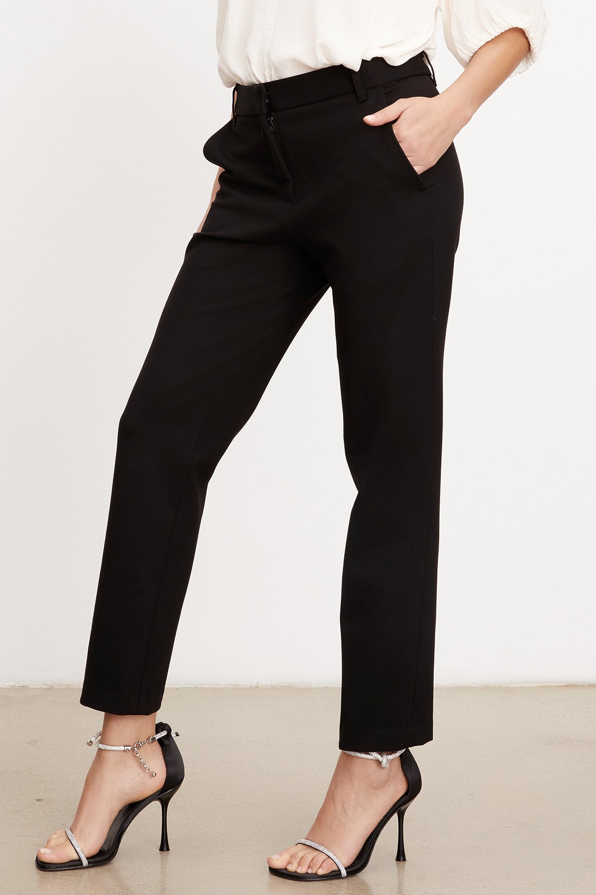   A woman wearing a white blouse and Velvet by Graham & Spencer JAY PONTI STRAIGHT LEG PANT. 