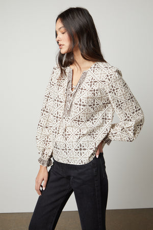 The model is wearing a Velvet by Graham & Spencer AUDETTE PRINTED BOHO TOP with a geometric pattern in earth tones.