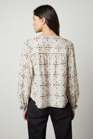 The back view of a woman wearing the Velvet by Graham & Spencer AUDETTE PRINTED BOHO TOP with a geometric pattern in earth tones.