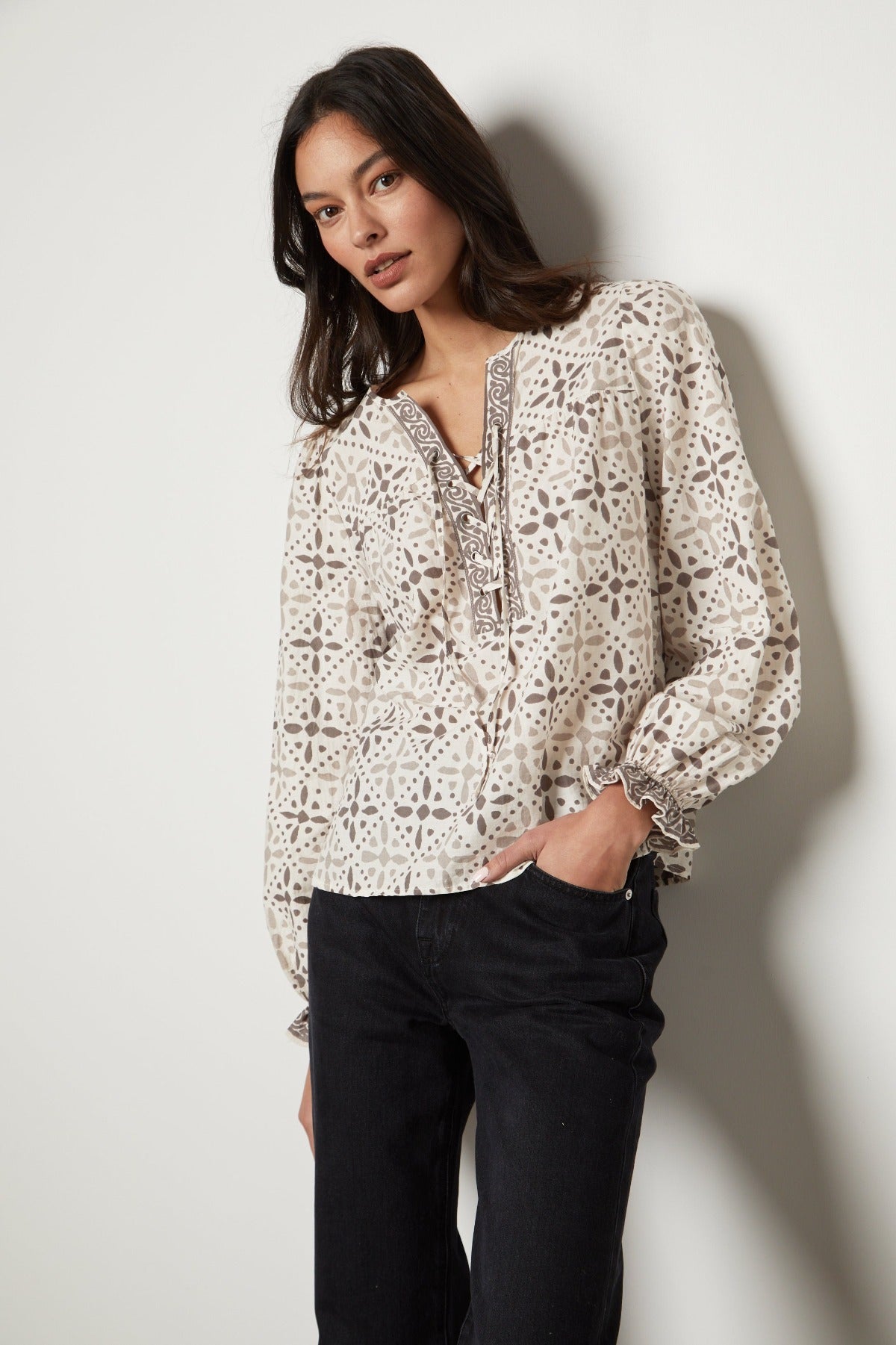   The model is wearing the Velvet by Graham & Spencer AUDETTE PRINTED BOHO TOP with a geometric pattern in earth tones. 