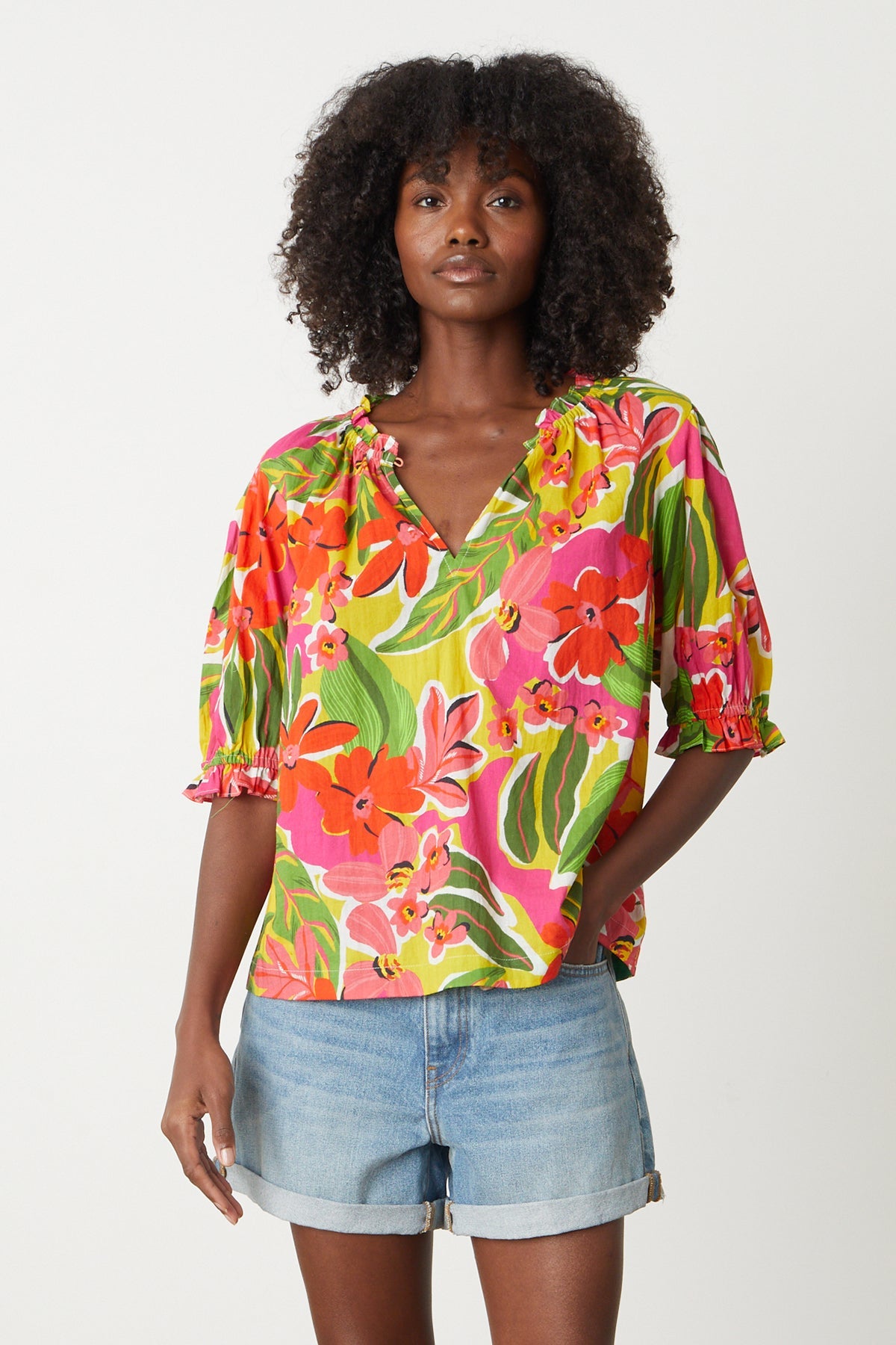 Carrie Boho Top in bold floral aloha print with reds, hot pinks and greens tucked into blue denim shorts, model's hand in denim pocket-26715112865985