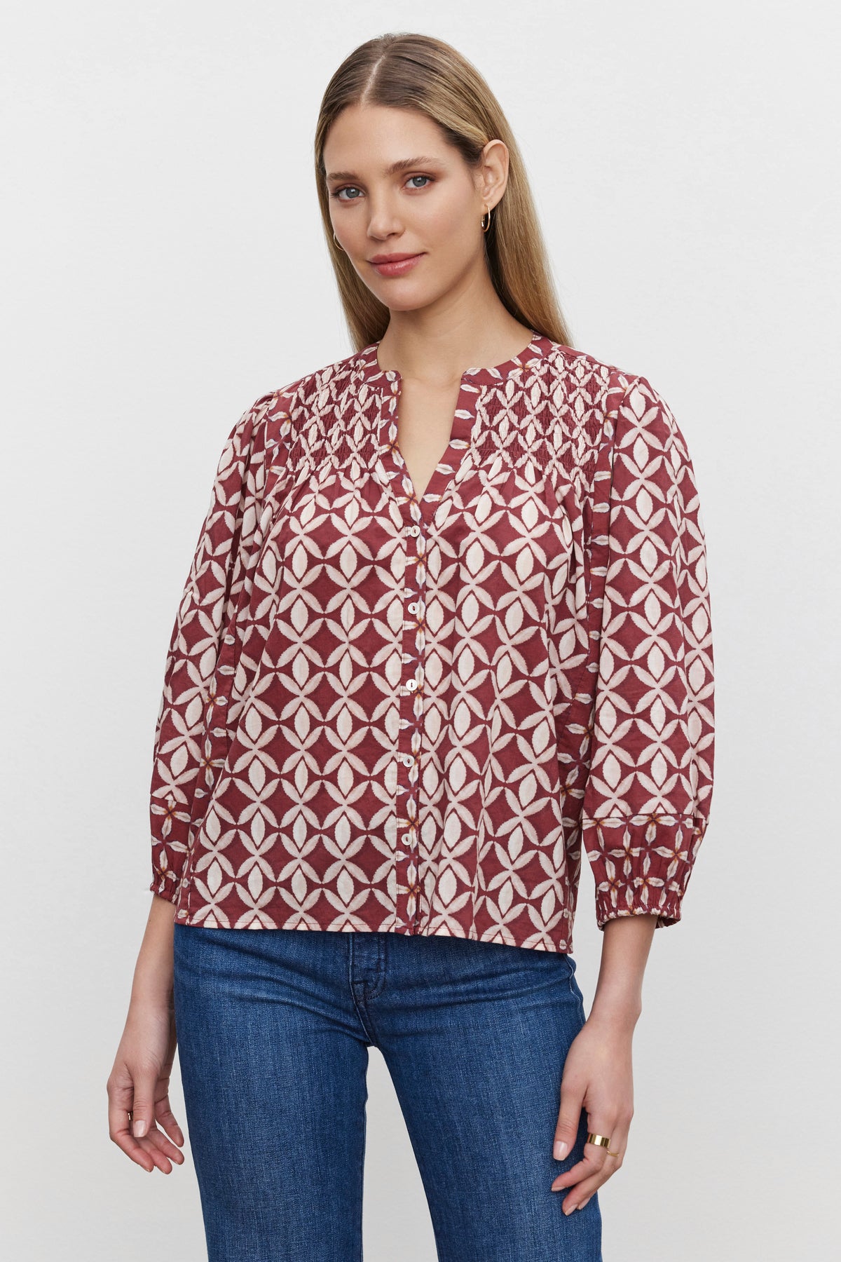   A woman with long, straight hair is wearing a maroon and white patterned HADDON TOP by Velvet by Graham & Spencer in printed cotton cambric and blue jeans, standing against a plain background. 