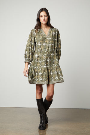 The model is wearing a KATARINA PRINTED BOHO DRESS by Velvet by Graham & Spencer with black boots.