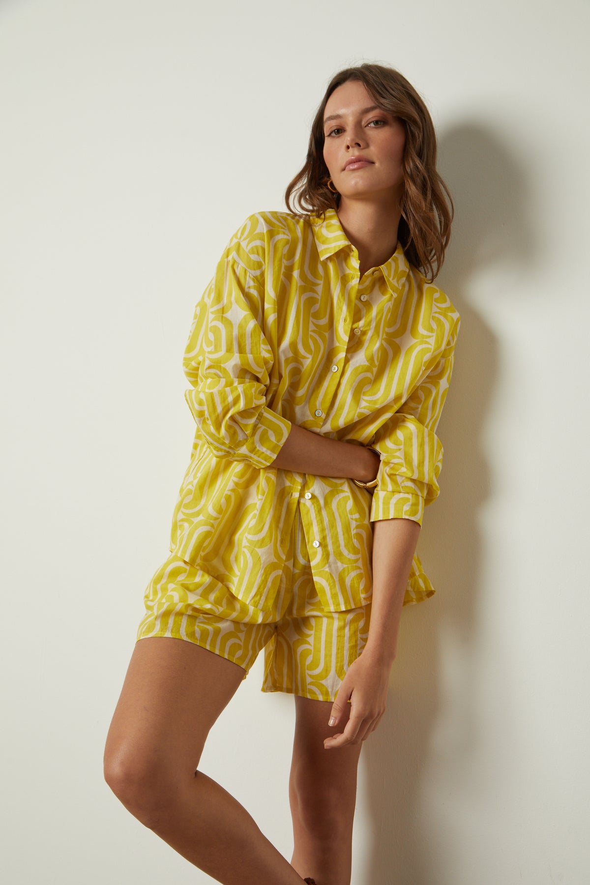   a woman in yellow Velvet by Graham & Spencer pyjamas leaning against a wall. 