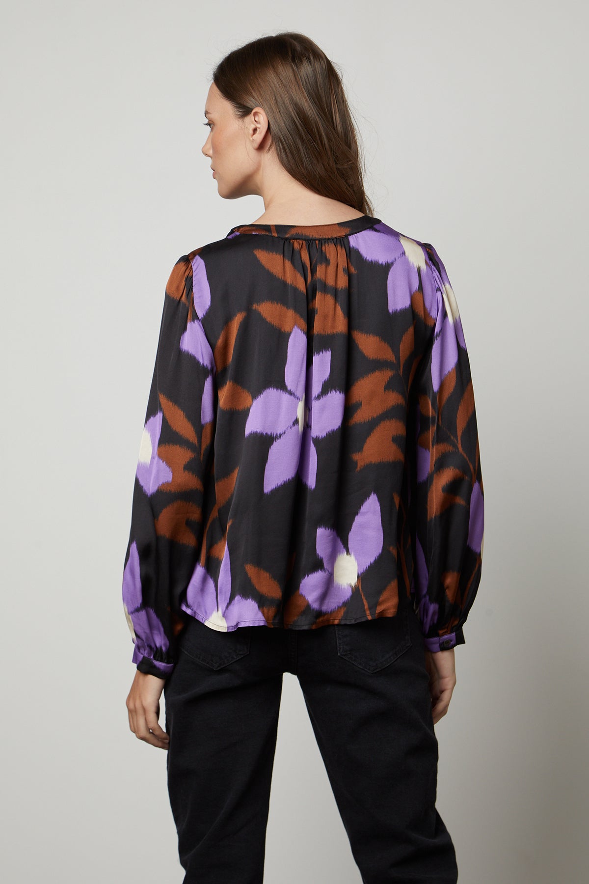 The back view of a woman wearing the Velvet by Graham & Spencer ISRA PRINTED V-NECK BLOUSE with purple flowers.-26914818064577