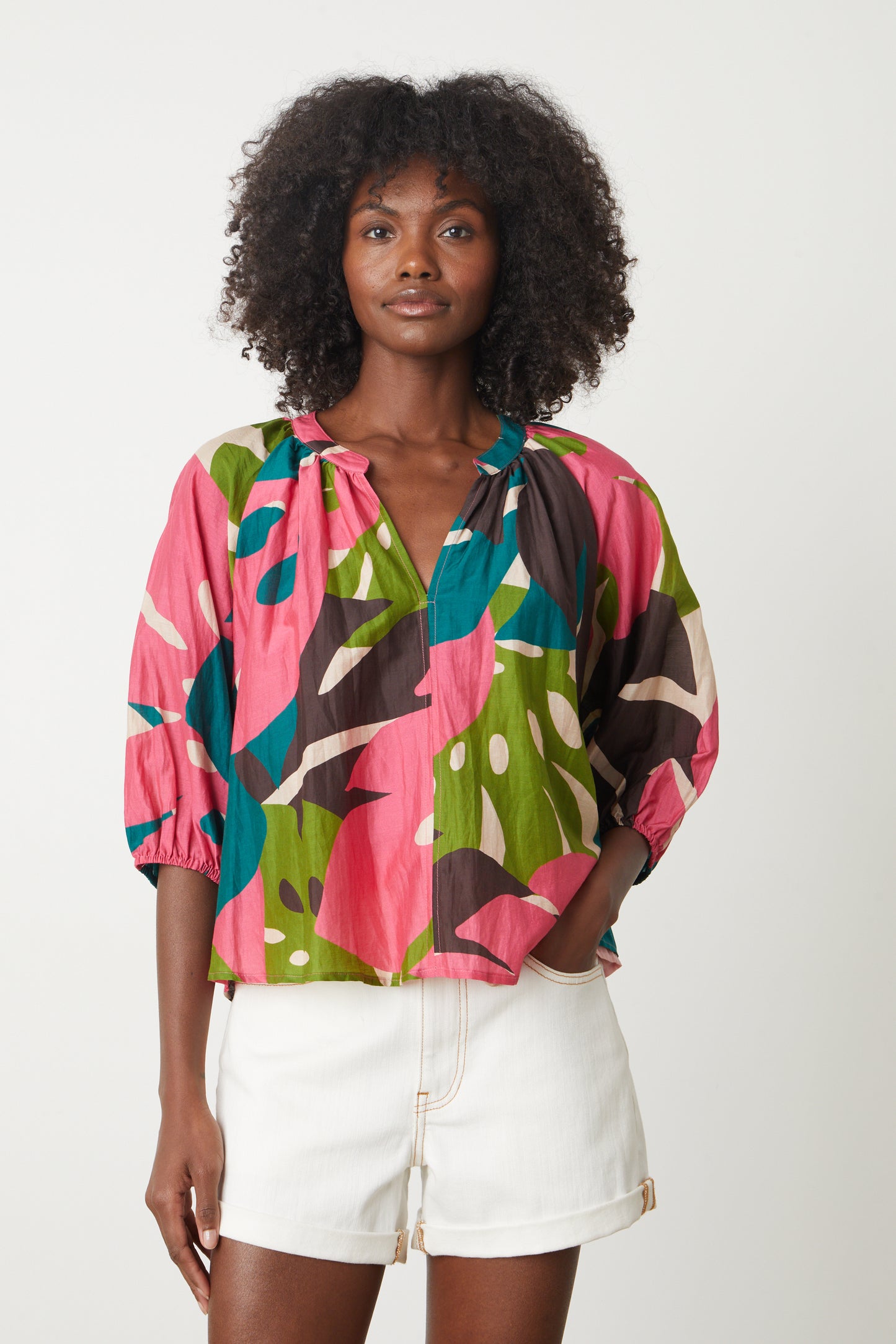 Woman wearing a Velvet by Graham & Spencer ARIEL PRINTED TOP blouse in brightly colored Monstera leaf print -26577405935809