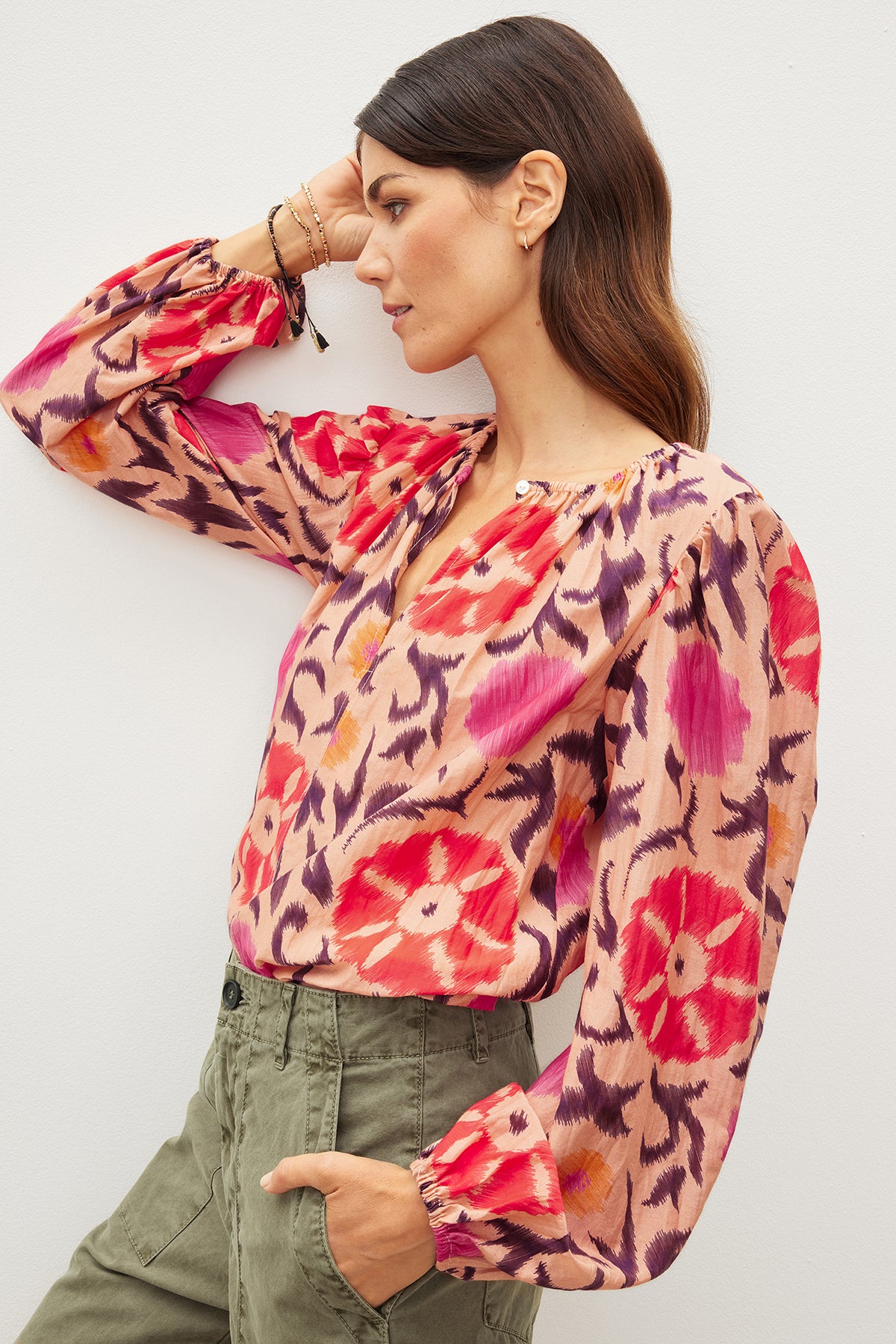 A woman in a FRASER PRINTED SILK COTTON VOILE TOP by Velvet by Graham & Spencer leaning against a wall.-35982328660161