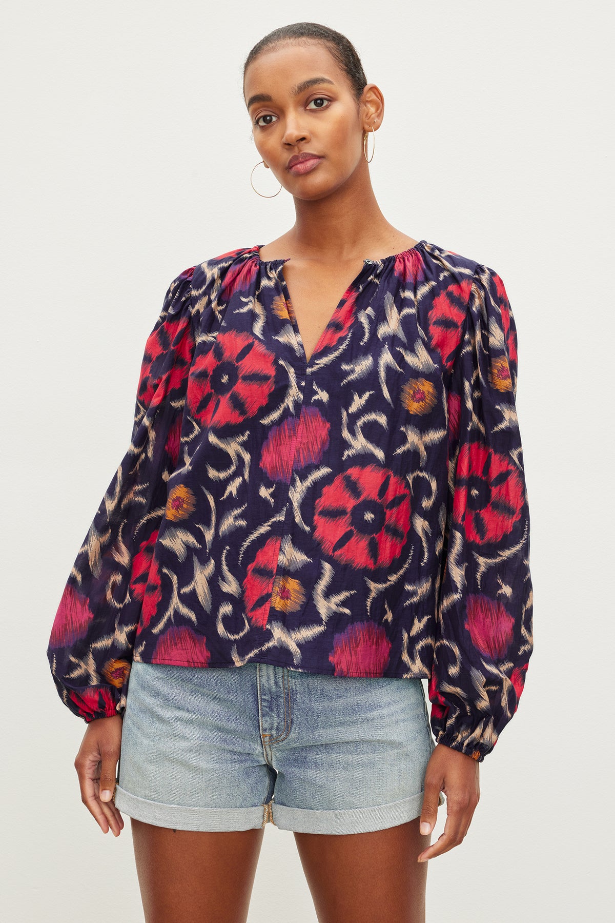   Woman posing in a Fraser printed silk cotton voile top by Velvet by Graham & Spencer with long sleeves and an elastic neckline, paired with denim shorts. 