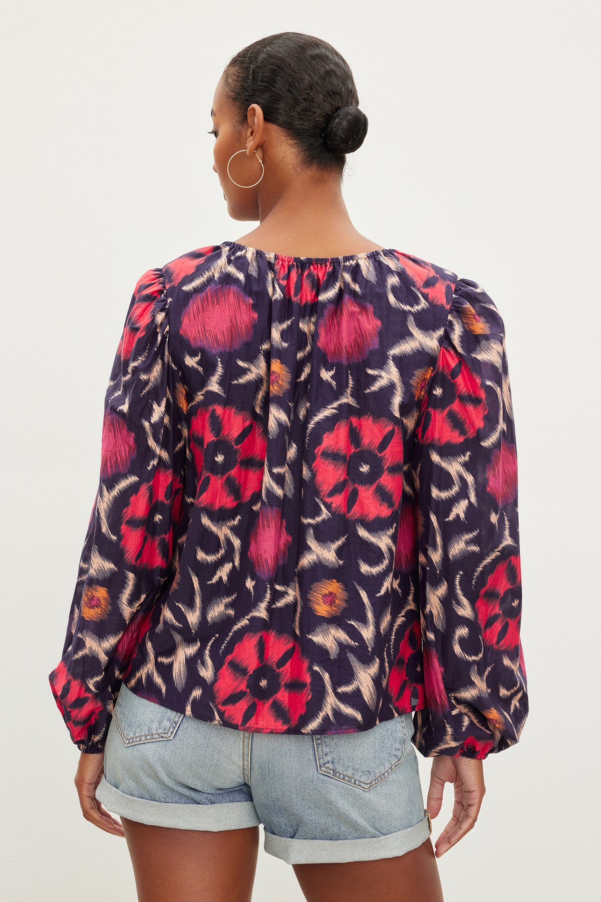   Woman from behind wearing a Fraser printed silk cotton voile top by Velvet by Graham & Spencer with long sleeves and denim shorts. 