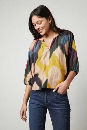 A woman wearing a Velvet by Graham & Spencer LIZETTE PRINTED BOHO TOP and jeans.