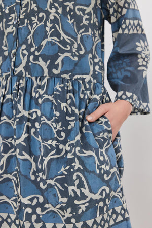 Close-up of a person in a blue and white floral Velvet by Graham & Spencer Talia dress, focusing on the midsection where a hand gently pinches the fabric.