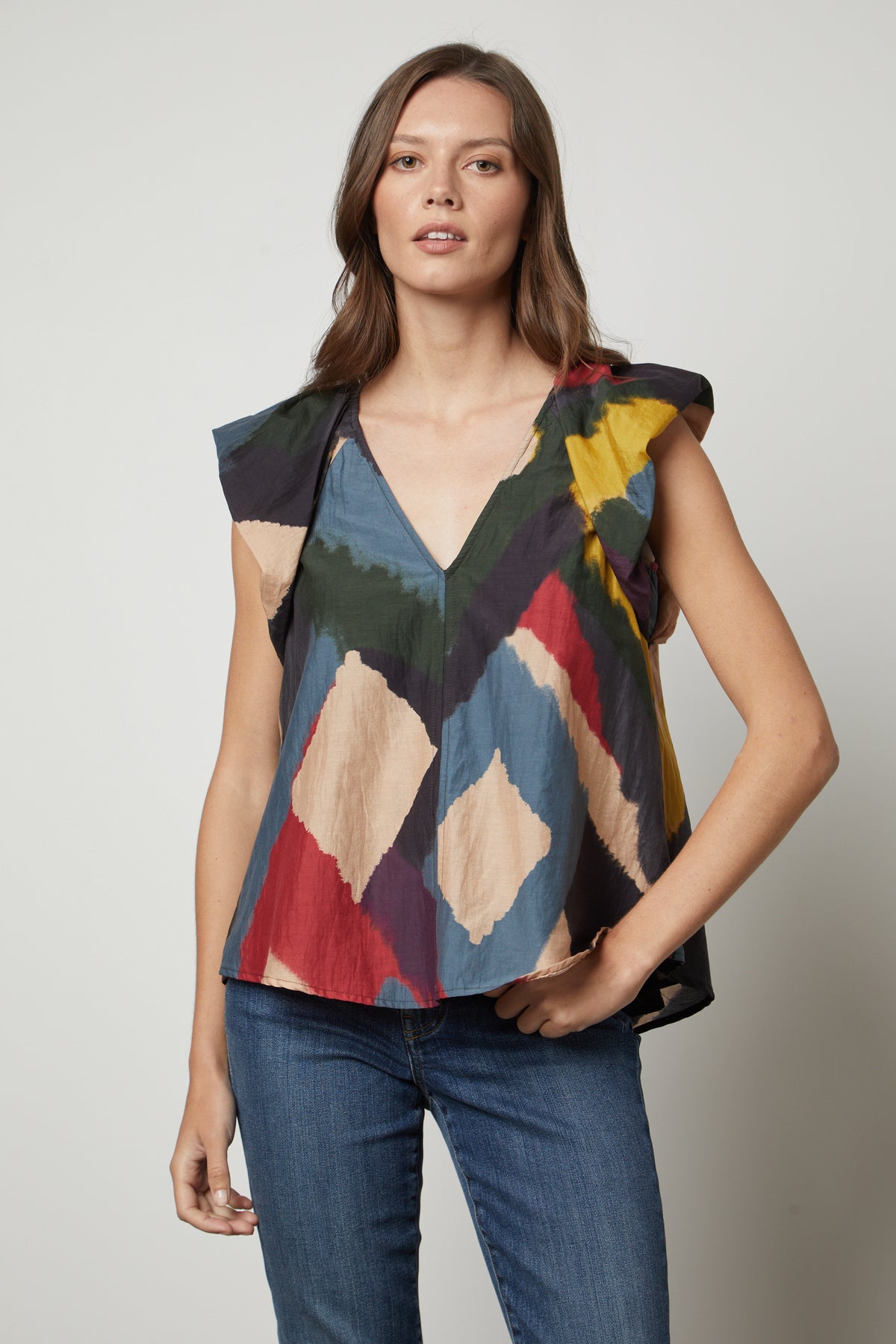 A woman wearing TAMARA PRINTED TOP from Velvet by Graham & Spencer jeans and a colorful voile top with flutter sleeves.-35655953875137