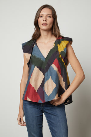 A woman wearing TAMARA PRINTED TOP from Velvet by Graham & Spencer jeans and a colorful voile top with flutter sleeves.