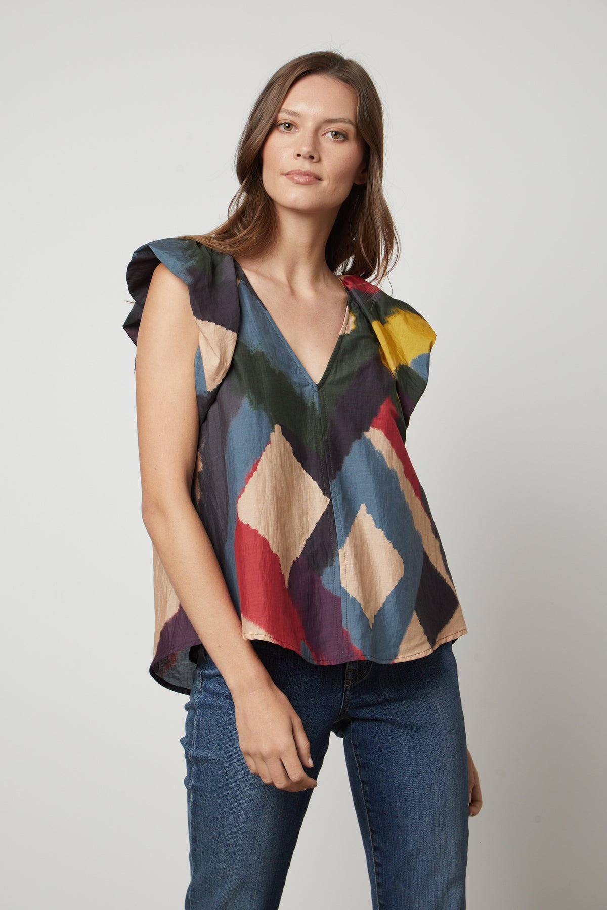   A woman wearing TAMARA PRINTED TOP by Velvet by Graham & Spencer jeans and a colorful silk cotton voile top with flutter sleeves. 