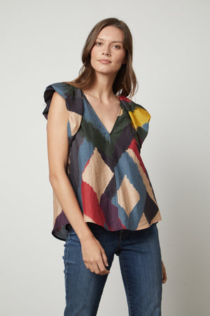 A woman wearing TAMARA PRINTED TOP by Velvet by Graham & Spencer jeans and a colorful silk cotton voile top with flutter sleeves.