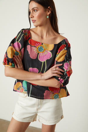 Jasmine Top in bold floral with black background and white denim shorts front close up woman arms folded in front