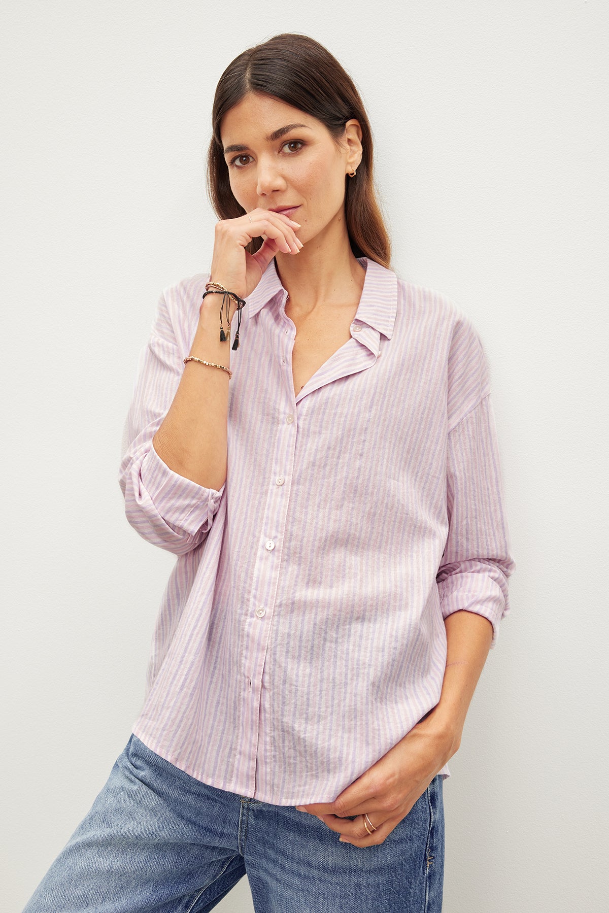 A woman showcasing her contemporary style with a Velvet by Graham & Spencer ASHLYN STRIPED BUTTON-UP SHIRT, a wardrobe staple for any fashion-forward individual.-35955417841857