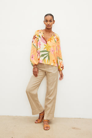 A woman wearing a Velvet by Graham & Spencer DION PRINTED BOHO TOP and tan wide leg pants.