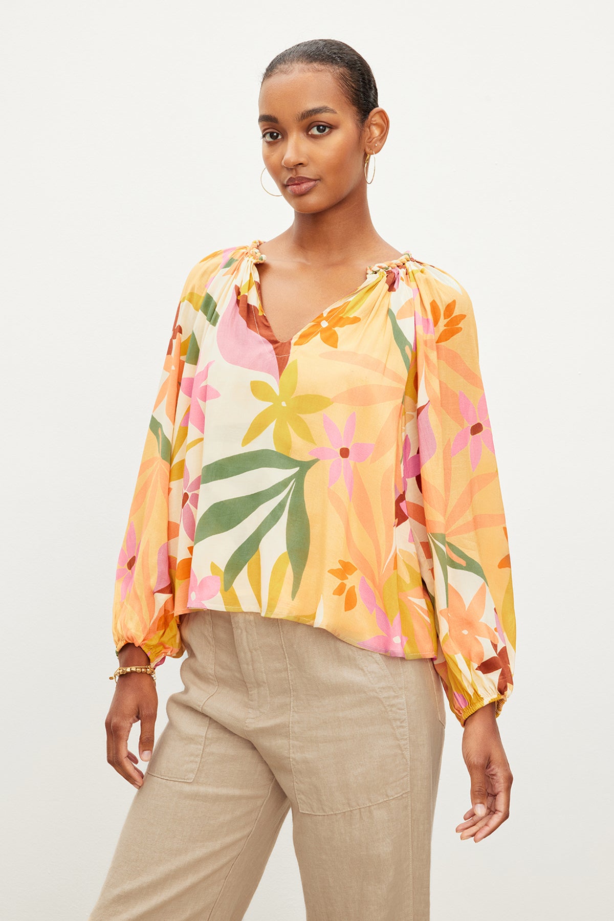   A model wearing the Velvet by Graham & Spencer DION PRINTED BOHO TOP with a tropical print and v-neckline. 