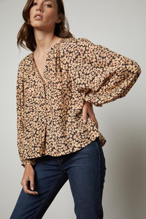 The model is wearing jeans and a MELINDA PRINTED BUTTON-UP TOP by Velvet by Graham & Spencer with a floral print.
