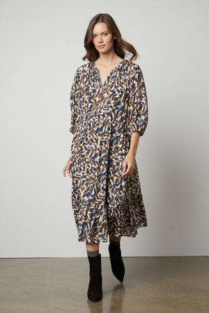 The model is wearing a Velvet by Graham & Spencer OTTILIE PRINTED BOHO DRESS.
