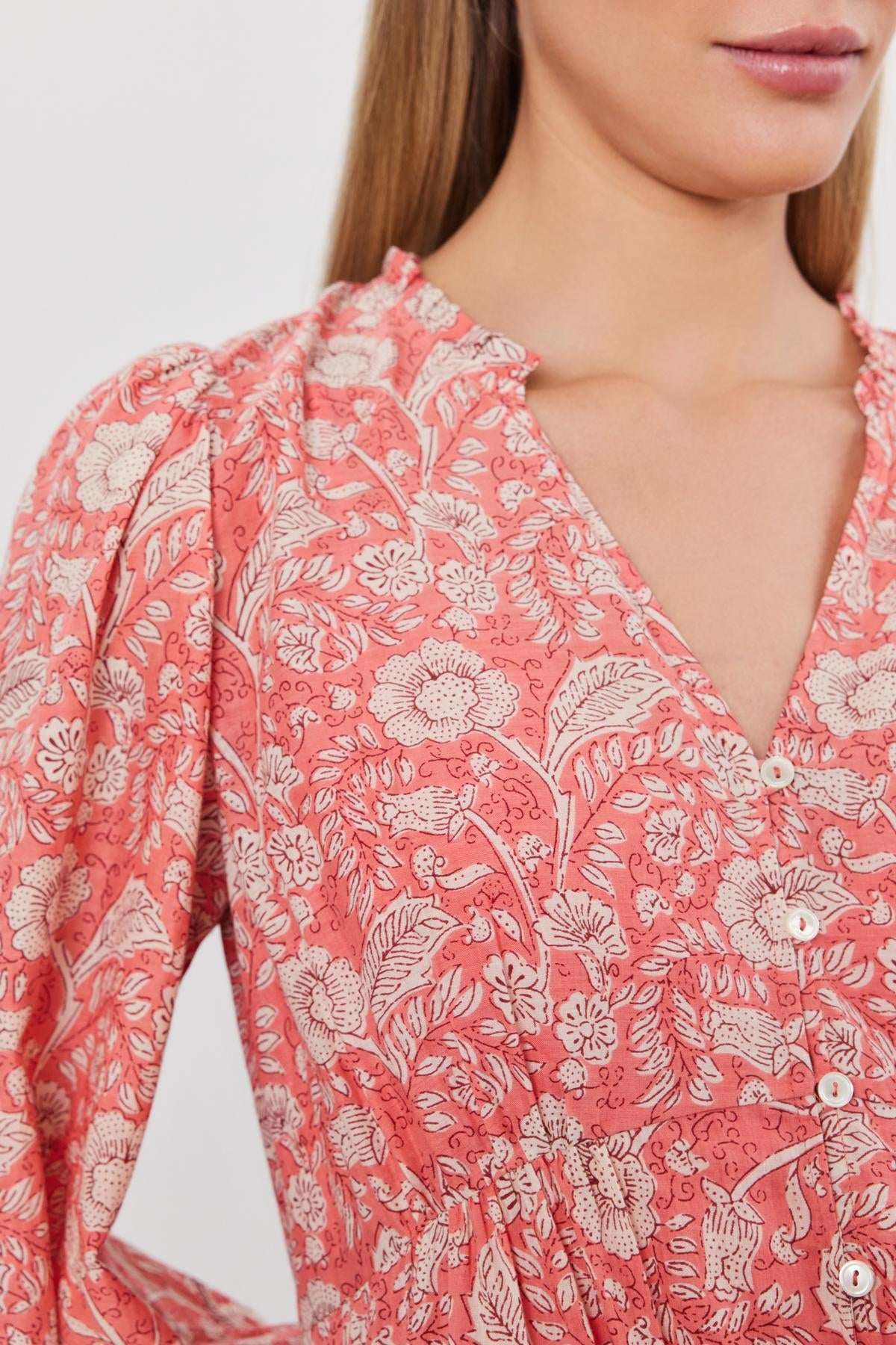 Close-up of a woman wearing a pink floral printed cotton voile MARY DRESS with a v-neckline and button details by Velvet by Graham & Spencer.-36910098972865