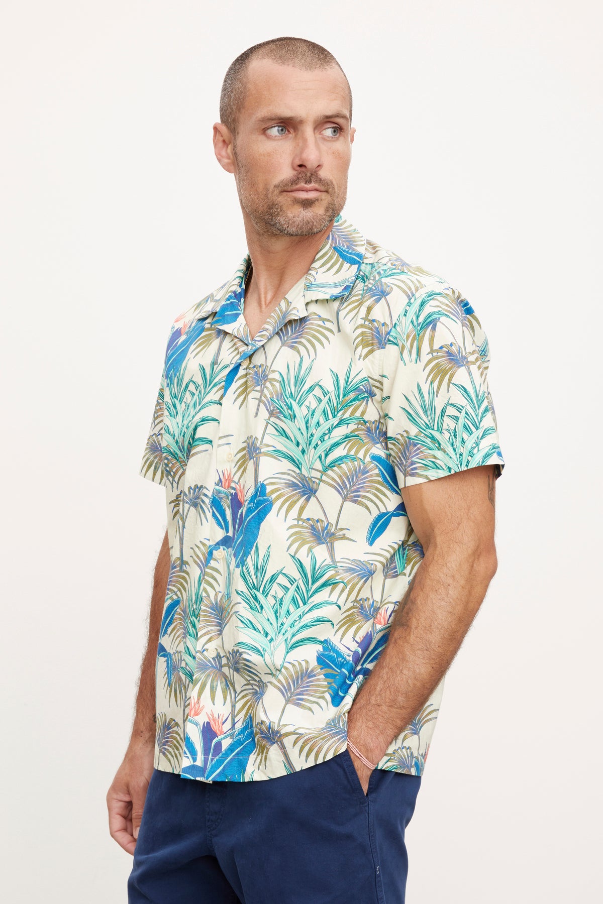   A man in a casual Iggy button-up shirt from Velvet by Graham & Spencer stands facing left, looking ahead with a neutral expression. 