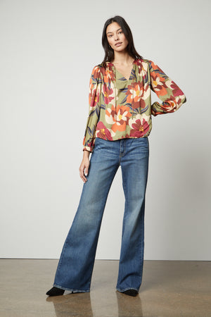 Woman standing in a pose wearing a Velvet by Graham & Spencer Isra Printed V-Neck Blouse and wide-leg jeans for a timeless look.