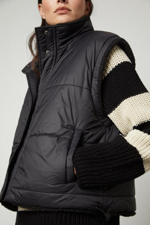 A woman wearing the Velvet by Graham & Spencer ALICIA REVERSIBLE PUFFER SHERPA VEST and sweater.
