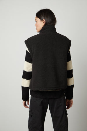 The back view of a woman wearing the Velvet by Graham & Spencer ALICIA REVERSIBLE PUFFER SHERPA VEST.