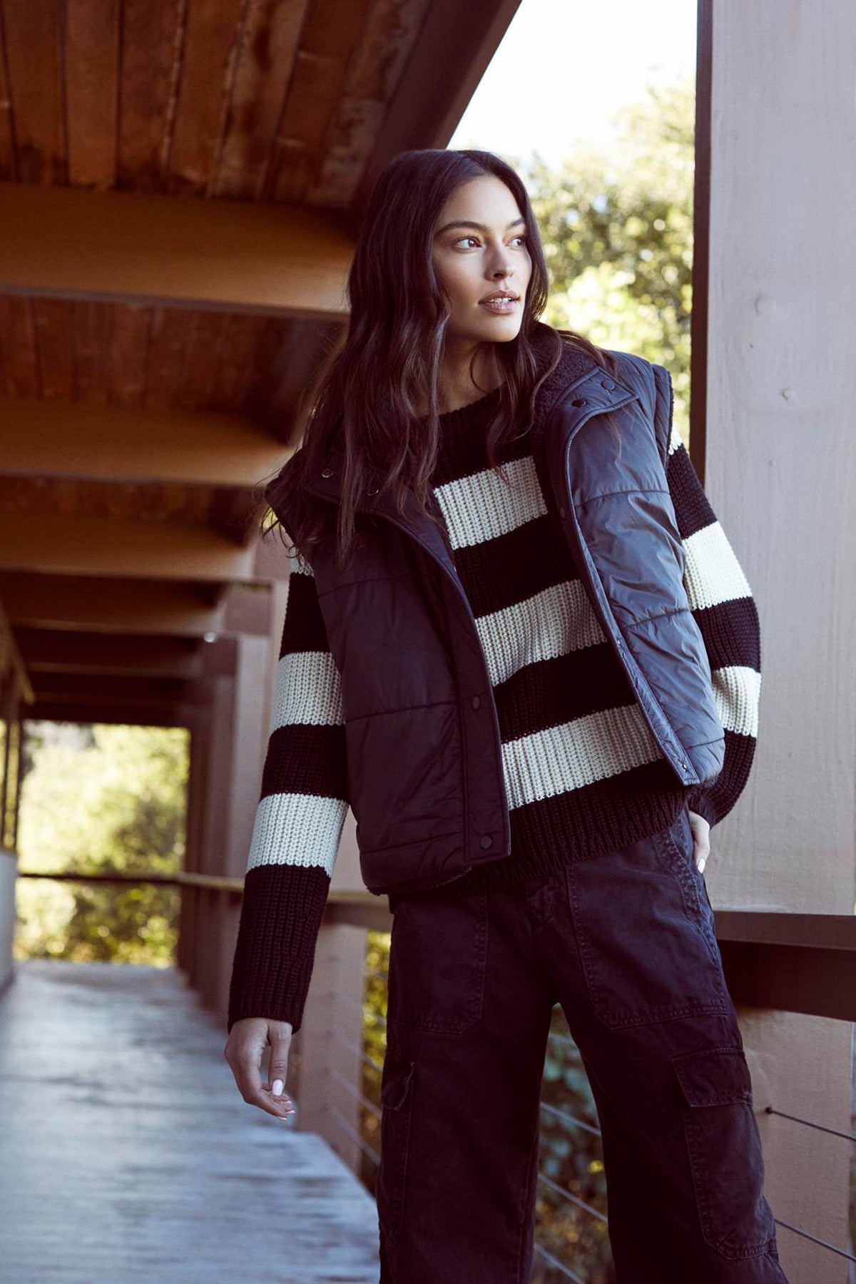 A woman wearing a striped sweater and Velvet by Graham & Spencer's ALICIA REVERSIBLE PUFFER SHERPA VEST for cold weather.-35224436408513