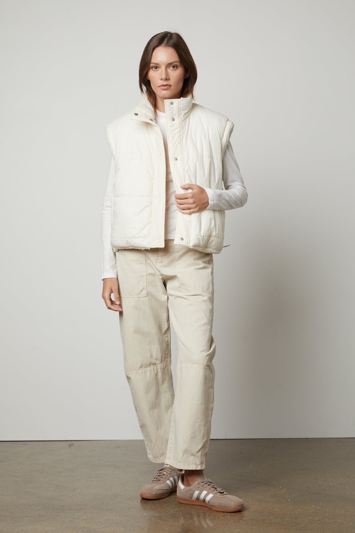   A model wearing a white puffer vest and BRYLIE SANDED TWILL UTILITY PANT by Velvet by Graham & Spencer with patch pockets. 