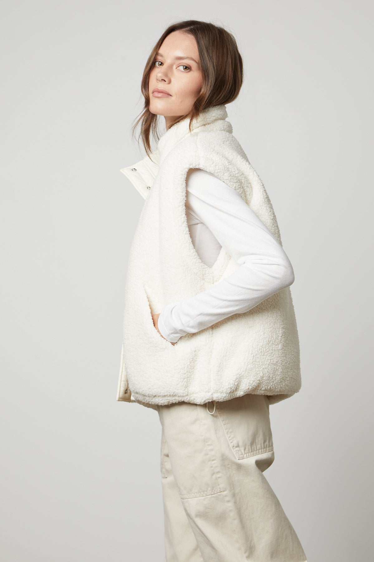   A woman wearing the ALICIA REVERSIBLE PUFFER SHERPA VEST by Velvet by Graham & Spencer, perfect for cold weather. 