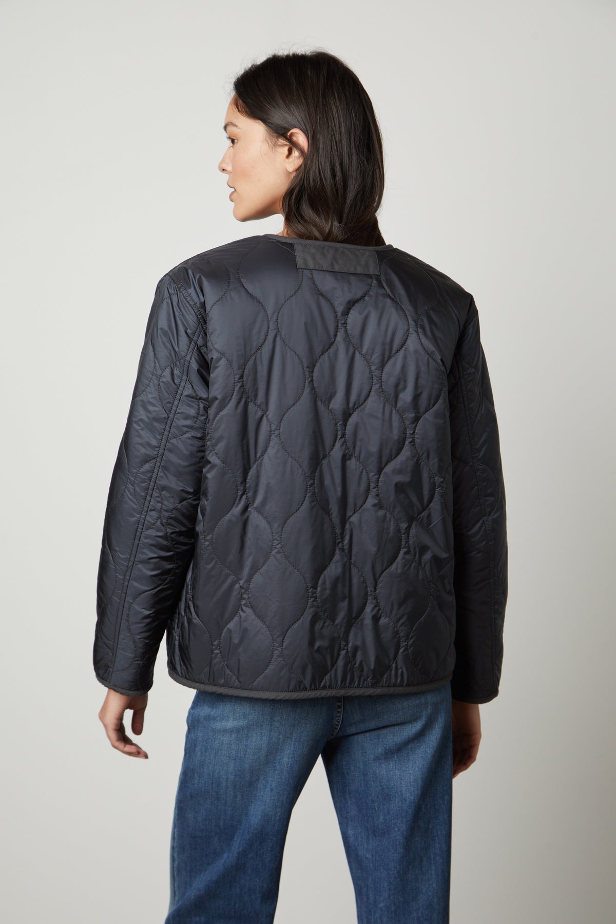 The back view of a woman wearing a Velvet by Graham & Spencer MARISSA REVERSIBLE QUILTED SHERPA JACKET.-26905625821377