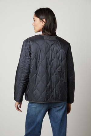 The back view of a woman wearing a Velvet by Graham & Spencer MARISSA REVERSIBLE QUILTED SHERPA JACKET.