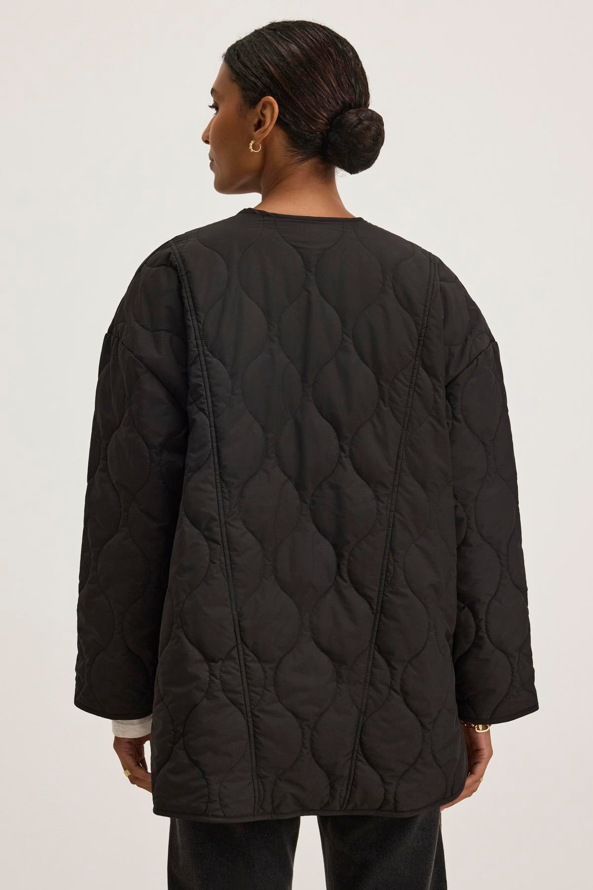   A person dressed in the PAITYN QUILTED JACKET from Velvet by Graham & Spencer, evocative of vintage military attire, is photographed from the back against a plain background. 