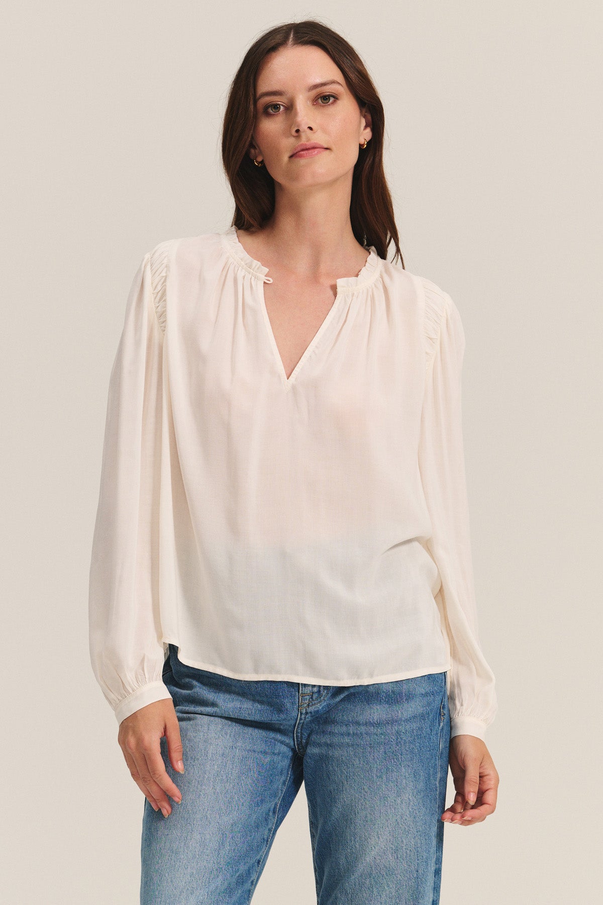 A woman wears the TAMARA BLOUSE by Velvet by Graham & Spencer, featuring a feminine ruffled neckline.-40681921085633