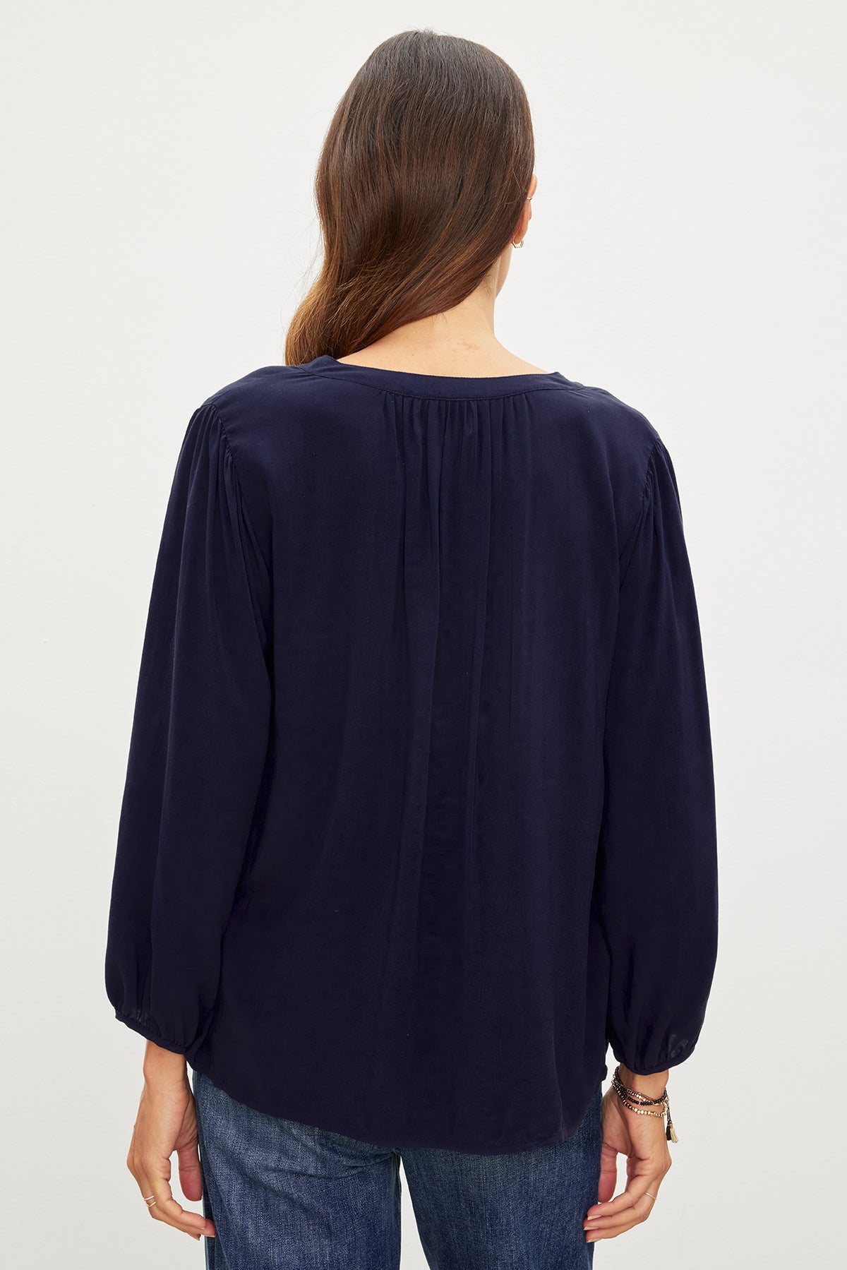 The back view of a woman wearing relaxed fit jeans and a Velvet by Graham & Spencer ASHLEY V-NECK TOP.-35955417120961