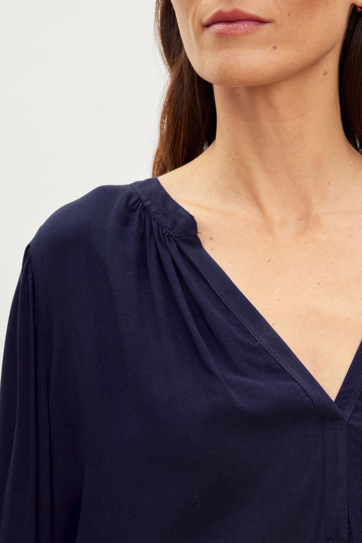 A woman wearing a blue Velvet by Graham & Spencer ASHLEY V-NECK TOP blouse.-35955417153729