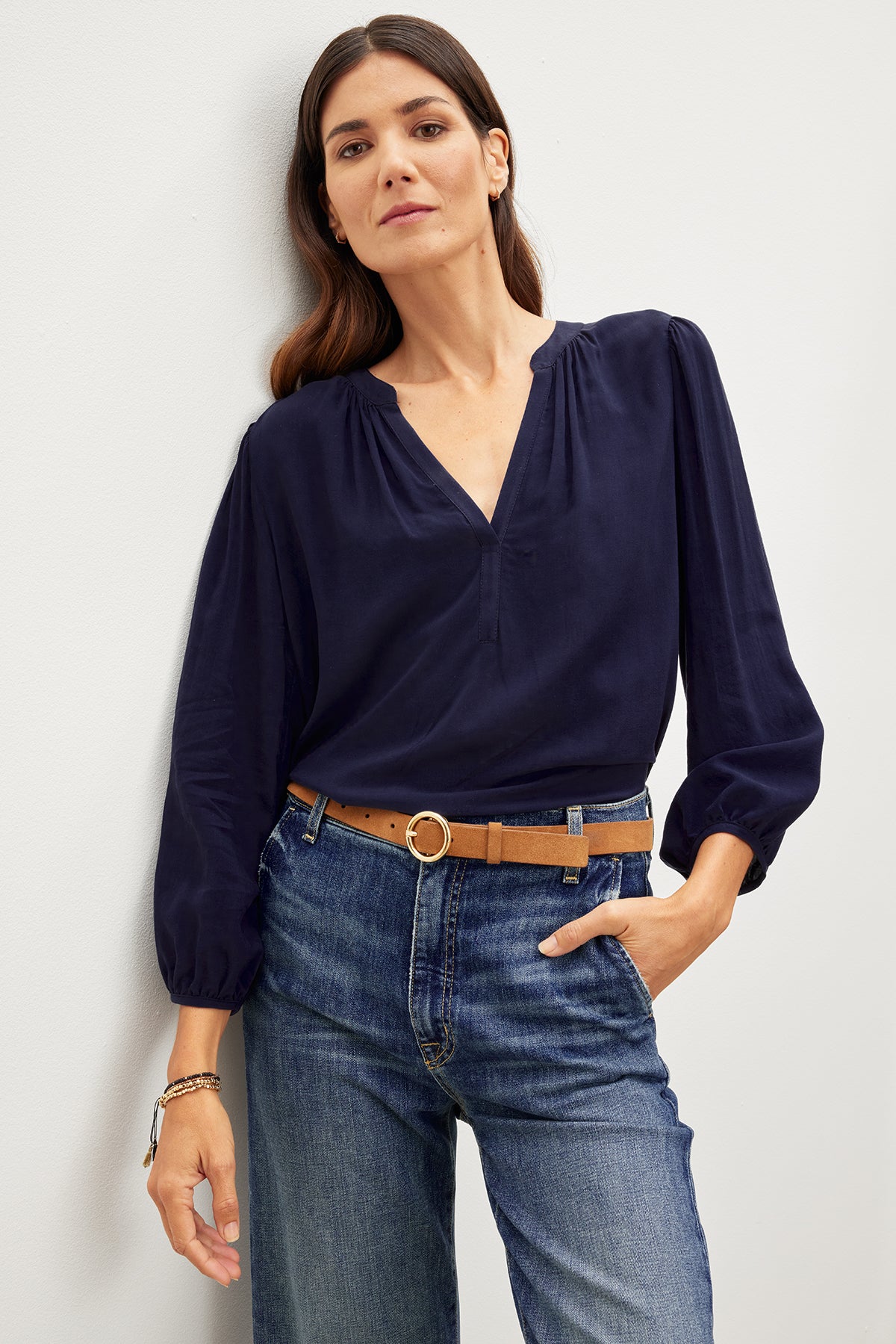   A woman wearing relaxed fit jeans and an ASHLEY V-NECK TOP by Velvet by Graham & Spencer. 