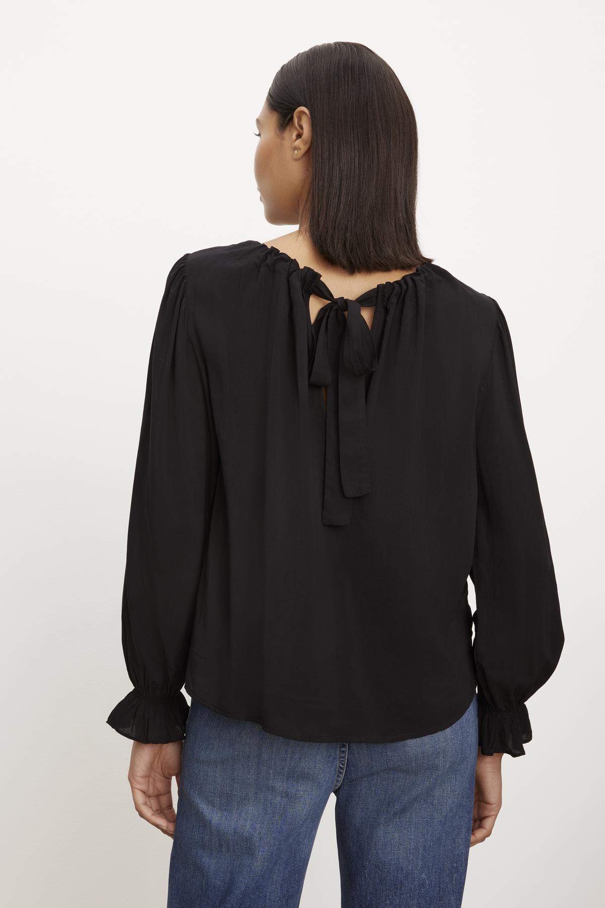 The back view of a woman wearing a Velvet by Graham & Spencer BRISTOL NECK TIE TOP with jeans.-36001351139521