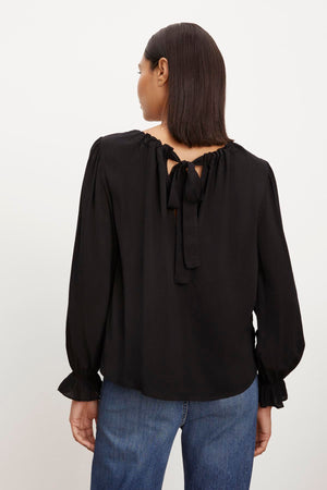 The back view of a woman wearing a Velvet by Graham & Spencer BRISTOL NECK TIE TOP with jeans.