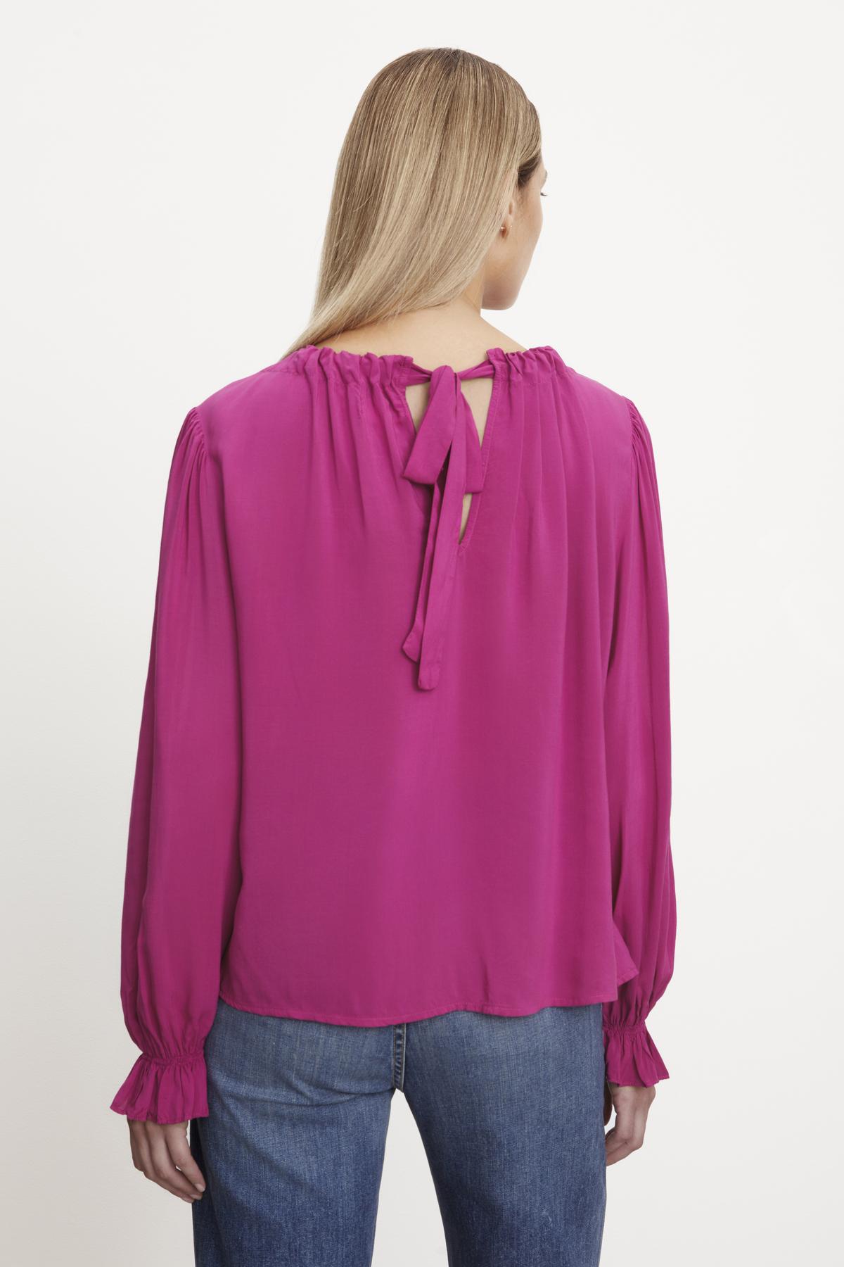   The back view of a woman wearing a luxurious Velvet by Graham & Spencer BRISTOL NECK TIE TOP with tie closure. 