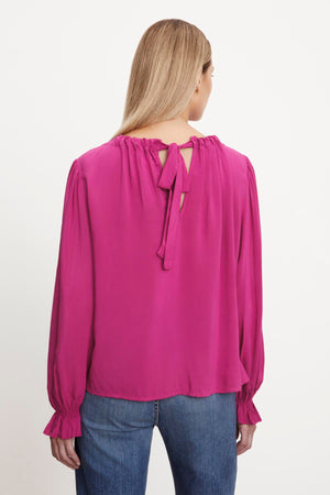 The back view of a woman wearing a luxurious Velvet by Graham & Spencer BRISTOL NECK TIE TOP with tie closure.