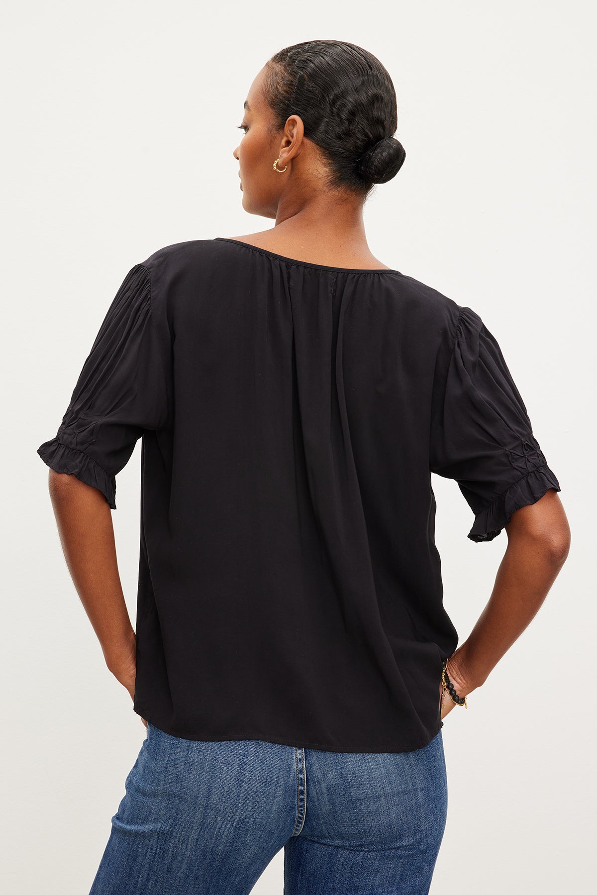 The back view of a woman wearing jeans and a Velvet by Graham & Spencer CALISSA SPLIT NECK BLOUSE.-35955490980033