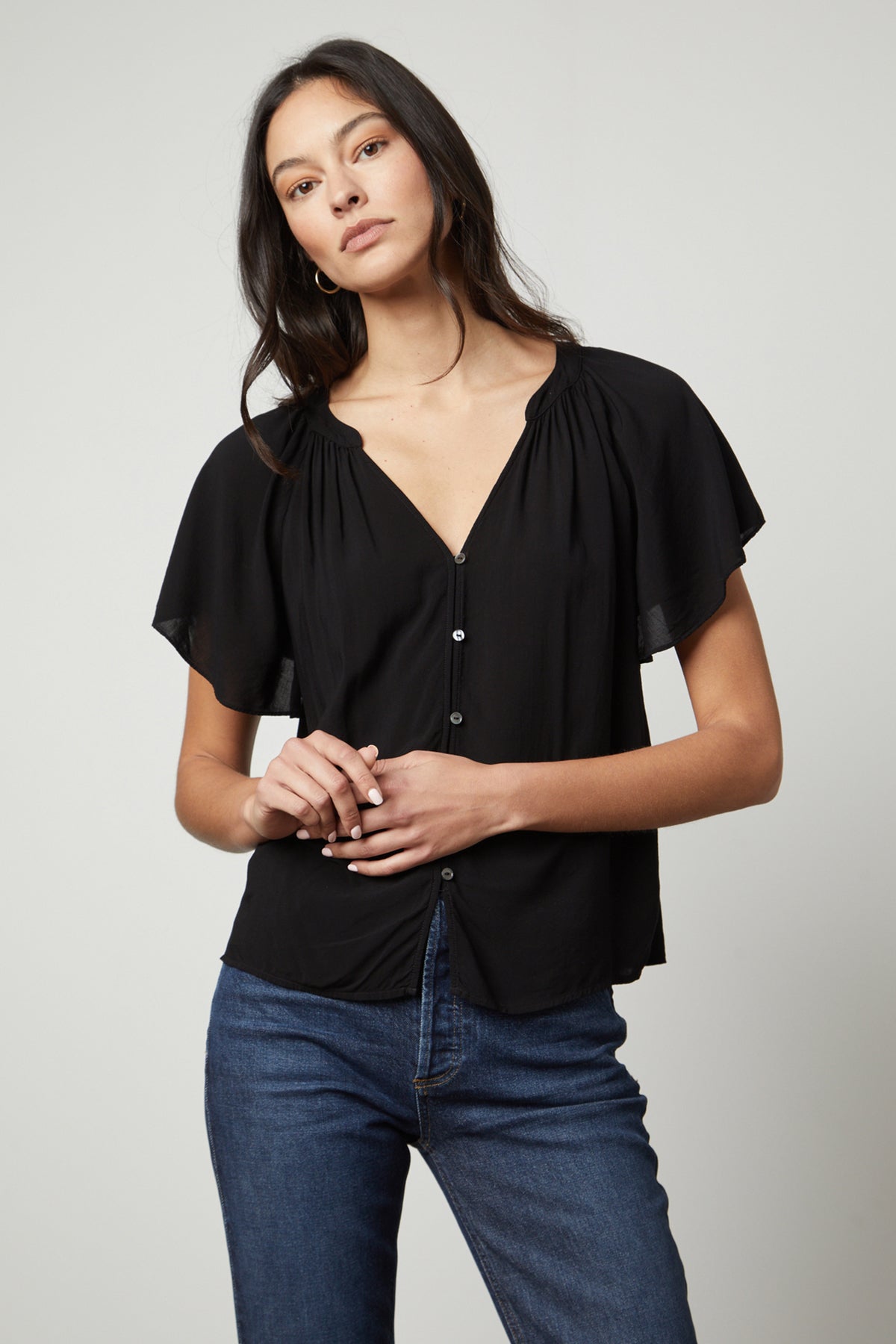   The model is wearing a Velvet by Graham & Spencer black blouse with ruffled sleeves, called the HARLEY FLUTTER SLEEVE TOP. 