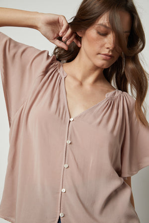 close up of model is wearing a Velvet by Graham & Spencer HARLEY FLUTTER SLEEVE TOP with buttons.